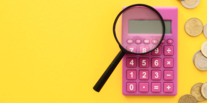 Magnifying glass on top of a pink calculator and yellow background - 4 Easy Ways to Refinance Your Home Loan