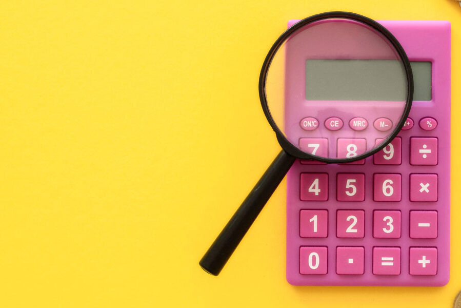 Magnifying glass on top of a pink calculator and yellow background - 4 Easy Ways to Refinance Your Home Loan