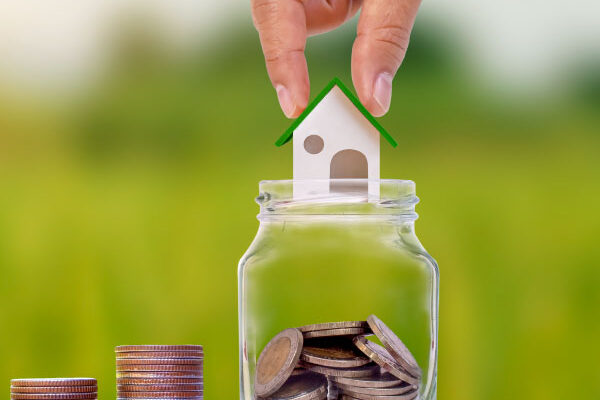 Hand holding a model house over a jar full of coins - DG Pinnacle Home Loans - Adjustable Rate Mortgage - Miami Mortgage Company