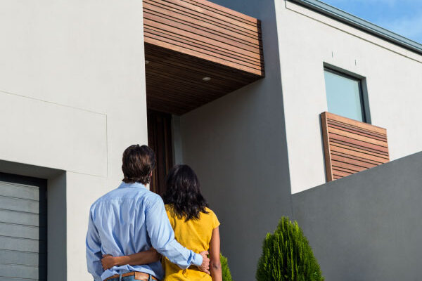 Young couple contemplating their new house from the outside - 30 Year Fixed Rate Mortgage - DG Pinnacle Home Loans - Miami Mortgage Company