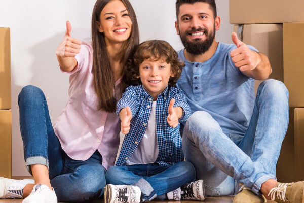 Happy young couple with their kid sitting next to moving boxes at their new home - 15 Year Fixed Rate Mortgage - DG Pinnacle Home Loans - Miami Mortgage Company
