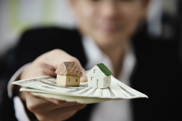 Loan Officer handing some money with a wooden model house on top - 4 Ways to Get Approved for an FHA Loan - DG Pinnacle Home Loans - Miami Mortgage Lender
