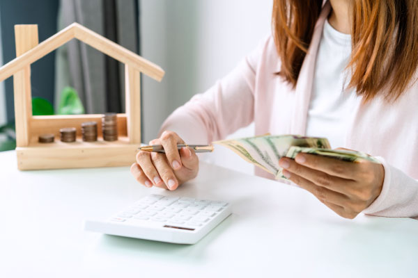 Young woman calculating the amount of money she's got from a cash-out refinance mortgage- DG Pinnacle Home Loans - Miami Mortgage Lender