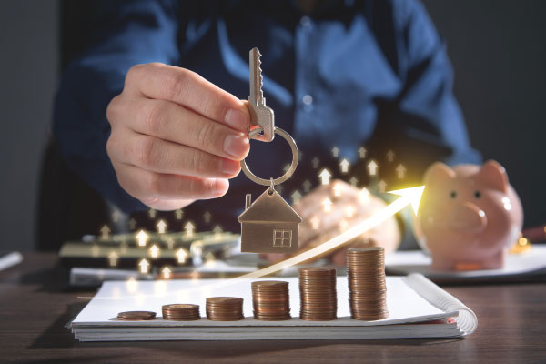 Concept photo of increasing prices for real estate market and a realtor showing a key with a key chain with a small house - DG Pinnacle Home Loans - Miami Mortgage Lender