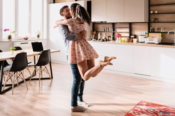 Happy young couple hugging in the middle of the living room of their new home - 5 steps for getting your mortgage pre-approved - DG Pinnacle Home Loans - Miami Mortgage Lender