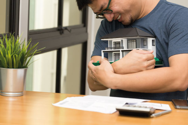 Happy young asian man hugging a model house - 5 steps for getting your mortgage pre-approved - DG Pinnacle Home Loans - Miami Mortgage Lender