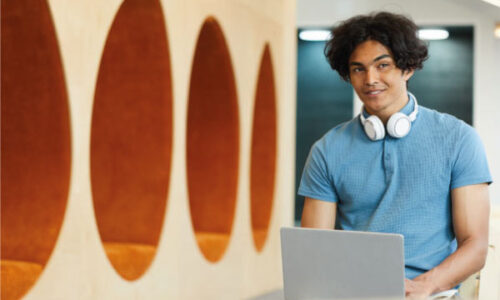 Smiling mixed race student sitting and working on a laptop - FHA Home Loans and Student Debt - DG Pinnacle - Miami Mortgage Lender