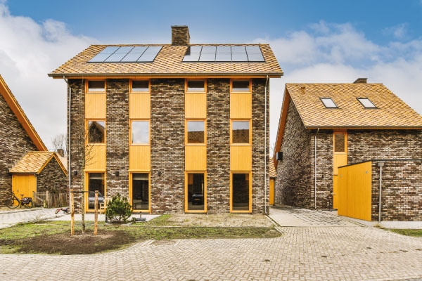 Front view of a beautiful bricks house and solar panels on the roof - 5 benefits of buying a home - DG Pinnacle Home Loans - Miami Mortgage Lender