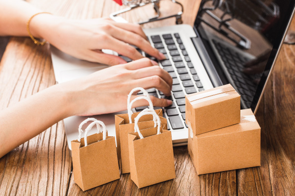 Concept of online shopping with laptop and female hands next to some cardboard boxes - 8 Credit Card Mistakes to Avoid at All Cost - DG Pinnacle Home Loans - Miami Mortgage Lender