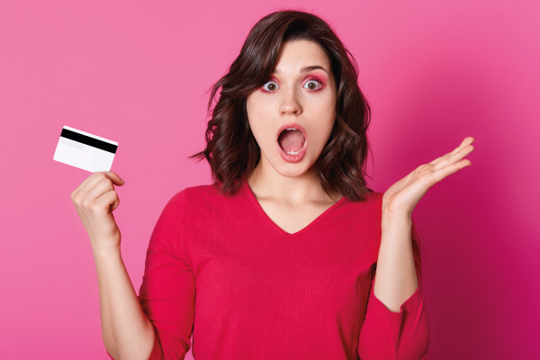 Astonished brunette woman being short of money because of her credit card- 8 Credit Card Mistakes to Avoid at All Cost - DG Pinnacle Home Loans - Miami Mortgage Lender