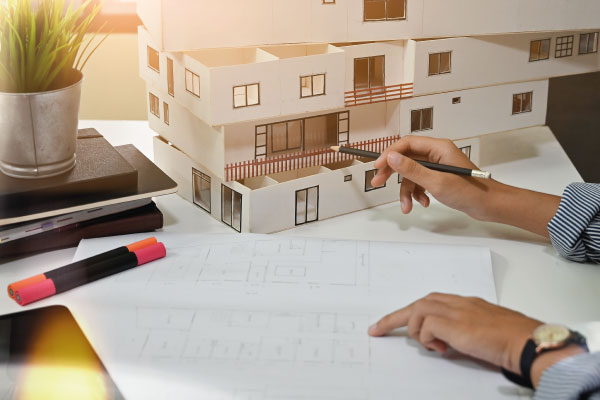 Female architect working with model house and blueprints - Who Can Become a Real Estate Investor? - DG Pinnacle Home Loans - Miami Mortgage Lender