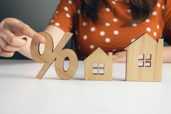 Female holding home model and wooden sale percentage sign - Home Prices Fell For First Time in 3 Years - DG Pinnacle Home Loans - Miami Mortgage Lender