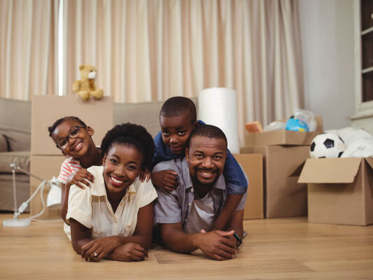 Happy family lying on top of each other on the floor - Top 7 Tax Benefits of Owning a Home - DG Pinnacle Home Loans - Miami Mortgage Lender