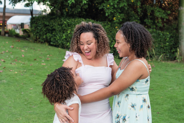 Latin Mom smiling next to her daughters in a garden | Do You Have to Be a U.S. Citizen to Get a Mortgage? | DG Pinnacle Home Loans - Miami Mortgage Lender