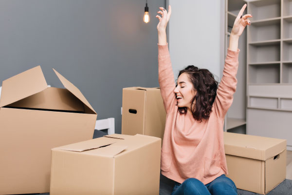 Happy young woman with some boxes moving to her new home | Single Women Own More Homes Than Single Men | DG Pinnacle Home Loans - Miami Mortgage Lender