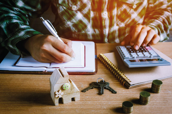 Man checking his finances with calculator next to a model house | What can I use to qualify | DG Pinnacle Home Loans - Miami Mortgage Lender