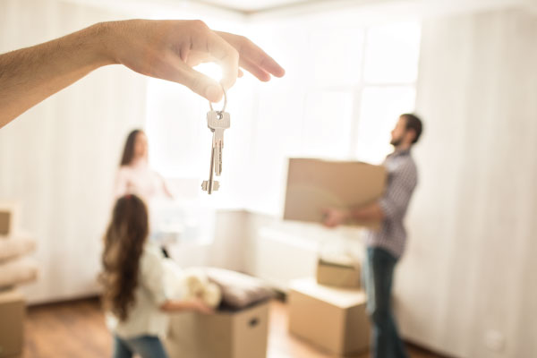 Hand holding some keys and happy family moving to their new house - How Long Does It Take To Close On A House? - DG Pinnacle Home Loans - Miami Mortgage Funding Lending Company