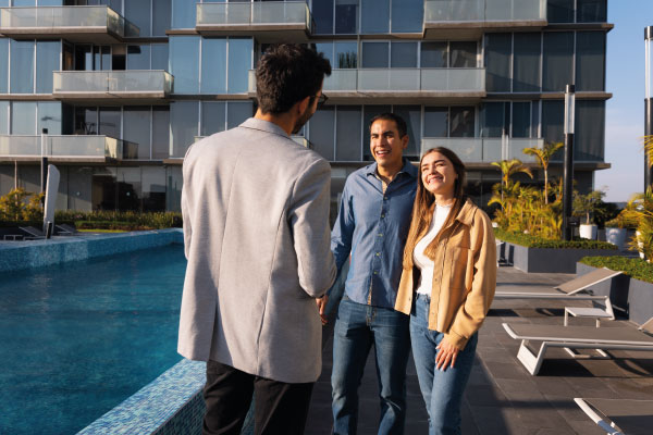 Young couple talking to a realtor next to condo apartaments pool | Advantages of Condos for First-Time Homebuyers | DG Pinnacle Home Loans - Miami Mortgage Funding Lender