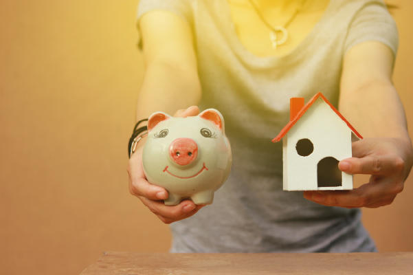Woman holding piggy bank with model house | Saving for a house | DG Pinnacle Home Loans - Miami Mortgage Lender