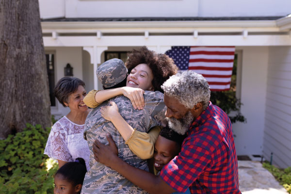 Proud and happy family hugging soldier back home - VA Home Loan Benefits | DG Pinnacle Home Loans | Miami Mortgage Lender