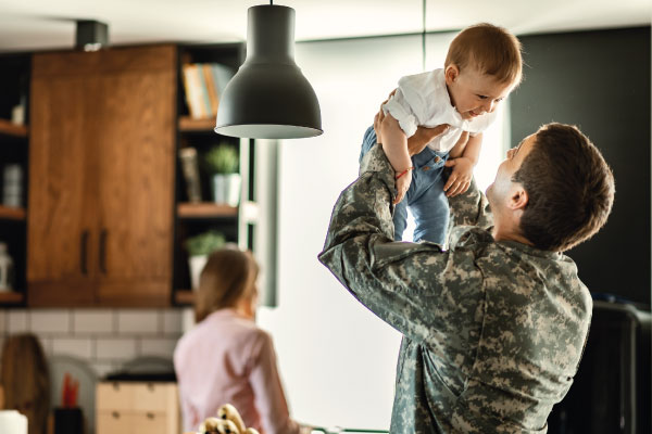 Happy baby having fun with his military dad and mom in background - VA Home Loan Benefits | DG Pinnacle Home Loans | Miami Mortgage Lender