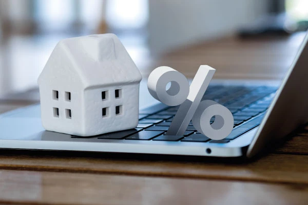 White model house with percentage sign and laptop | DG Pinnacle Home Loans - DSCR Mortgage Loans - Miami Mortgage Company