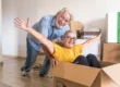 Senior couple having fun with a cardboard box | Should I Payoff My Mortgage Before I Retire? | DG Pinnacle Home Loans - Miami Mortgage Lender