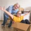 Senior couple having fun with a cardboard box | Should I Payoff My Mortgage Before I Retire? | DG Pinnacle Home Loans - Miami Mortgage Lender