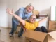 Senior couple having fun with a cardboard box | Should I Payoff My Mortgage Before I Retire? | DG Pinnacle Home Loans - Miami Mortgage Lender